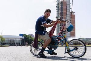 giovane uomo con su misura bicicletta Spettacoli via il suo stile equitazione giù il strada su un' soleggiato giorno. foto