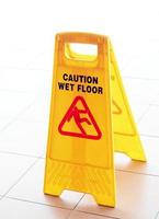 una barriera di plastica gialla che avvisa le persone di un pavimento bagnato