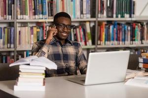 studente maschio parlando al telefono in biblioteca foto