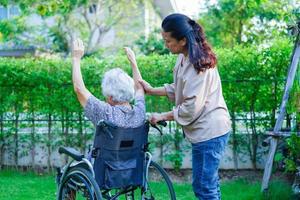 esercizio del paziente di disabilità della donna anziana asiatica sulla sedia a rotelle con il medico nel parco, concetto medico. foto