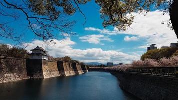 il dintorni di osaka castello nel primavera stagione con bellissimo cielo, calma fiume e ciliegia fiore. foto