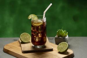 Cuba libre bevanda con lime e ghiaccio su rustico di legno tavolo foto