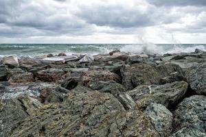 mare nel tempesta su rocce riva foto