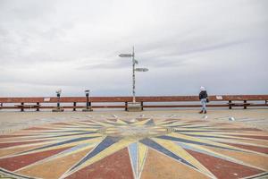 dipinto bussola design su il terra su un' passerella vicino il oceano foto