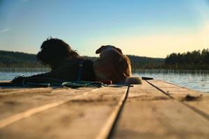 cane Gli amanti dire bugie su un' molo e guardare a il lago nel Svezia. Goldendoodle e mescolare foto