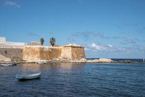 barca ormeggiato su mare con conca bastione nel sfondo su isola durante soleggiato giorno foto