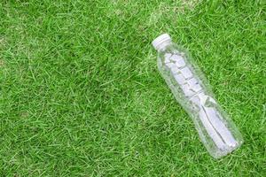 plastica bottiglia su verde erba sfondo riciclare e inquinamento concetto foto