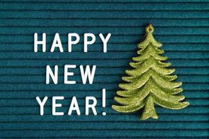 contento nuovo anno , testo su buio turchese provato lettera tavola con bianca lettere e verde giocattolo abete foto