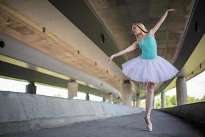 graziosa ballerina facendo esercizi di danza su un ponte di cemento foto