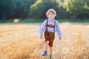 ragazzino divertente in pantaloncini di pelle a piedi campo di grano
