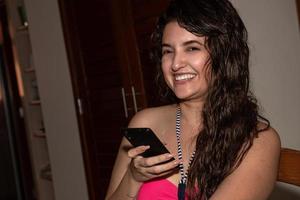 sorridente ragazza mentre A proposito di a cellulare smartphone foto