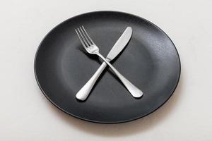 nero piatto con attraversamento coltello, cucchiaio su bianca foto
