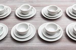 parecchi bianca tazze e piattini su grigio Marrone tavola foto