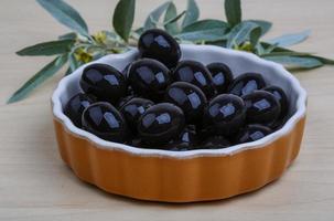 nero olive nel un' ciotola su di legno sfondo foto