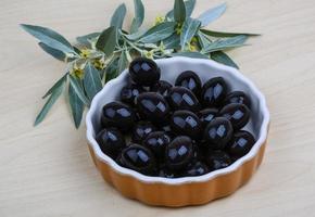 nero olive nel un' ciotola su di legno sfondo foto
