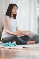 Dumbbelsl sul pavimento con la donna che fa meditazione foto