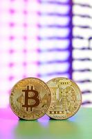 Due oro bitcoin menzogna su il verde superficie su il sfondo di il Schermo, quale Spettacoli il processi di estrazione il crypto moneta foto