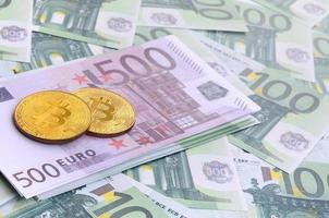 d'oro fisico bitcoin è bugie su un' impostato di verde monetario denominazioni di 100 euro. un' lotto di i soldi le forme un infinito mucchio foto