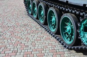 un' militare veicolo su bruco brani sta su un' piazza di pavimentazione pietre. foto di verde bruchi con metallo ruote quello ruotare loro