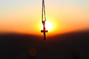 sagoma pendente croce davanti al tramonto foto