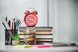 avvicinamento formazione scolastica oggetto con pila i soldi moneta-contanti dollaro e bicchiere vaso su sfondo. concetto per Salvataggio i soldi reddito per studia, calcolatore alunno finanza costi e investimento bilancio prestito foto