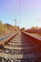 autunno industriale paesaggio. ferrovia sfuggente in il distanza tra verde e giallo autunno alberi foto