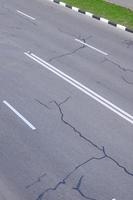 danneggiato cattivo asfalto strada con buche. toppa riparazione di asfalto foto