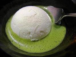 vicino su Noce di cocco ghiaccio crema nel matcha verde tè servito nel un' buio ciotola, famoso giapponese matcha dolce menù foto