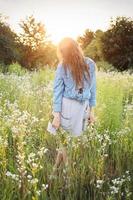 bella ragazza che cammina sul campo in estate con fiori di campo. foto