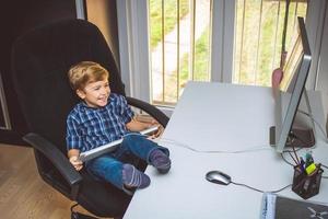 contento ragazzo con piedi su di tavolo giocando Giochi su computer. foto
