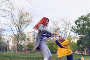 giocoso madre e figlio avendo divertimento e Filatura nel parco. foto