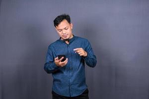 contento asiatico uomo digitando sms su grigio sfondo. isolato, attività commerciale concetto foto