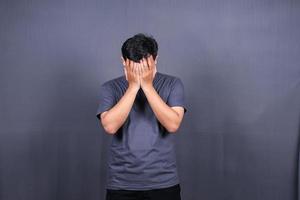 depresso asiatico giovane uomo avendo stressante tempo con mani copertura viso. isolato su grigio sfondo. foto