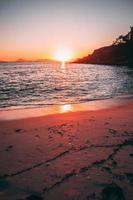 tramonto colorato su acqua e spiaggia