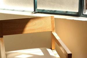 un' sedia moderno legna telaio con di legno, luce del sole In arrivo attraverso il finestra illuminante il sedia foto
