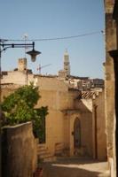 Visualizza a vecchio edifici, muri, tetti e roccia con religioso attraversare nel antico cittadina, sassi de matera, Italia. foto