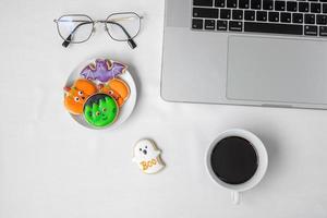 biscotti di Halloween, caffè caldo e computer portatile su sfondo bianco. buon halloween, shopping online, ciao ottobre, autunno autunno, festivo, festa e concetto di vacanza foto