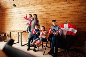 famiglia con bandiere danimarca all'interno della casa di legno. viaggiare nei paesi scandinavi. i danesi più felici. foto