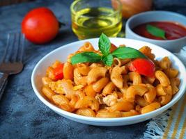 maccheroni pasta con pomodoro salsa nel bianca piatto su grigio colore tavolo foto