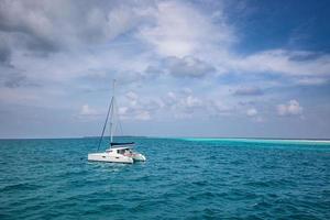 bellissimo turchese acqua in giro bianca barca a vela ancorato nel mezzo di oceano. nuvoloso cielo, oceano laguna. avventura viaggiare, ricreativo paesaggio marino. lusso attività, bianca yacht foto