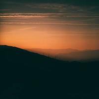 silhouette di montagne sotto il cielo arancione foto