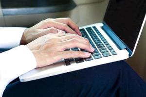 uomo d'affari che lavora al computer portatile mentre è seduto sul sedile del conducente in auto. concetto di stile di vita. foto