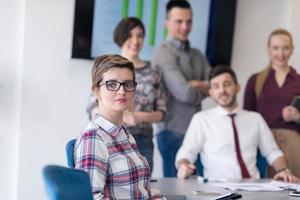 ritratto di giovane attività commerciale donna a ufficio con squadra su incontro nel sfondo foto