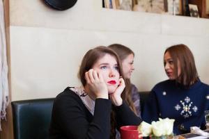 giovane donna ignorata dai suoi amici in caffetteria foto