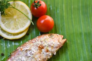 frutti di mare grigliato pesce con sale cibo e Limone prezzemolo pomodoro su Banana foglia sfondo foto