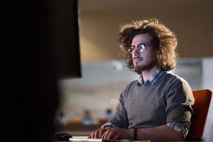 uomo Lavorando su computer nel buio ufficio foto