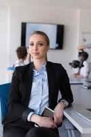 ritratto di giovane attività commerciale donna a ufficio con squadra su incontro nel sfondo foto