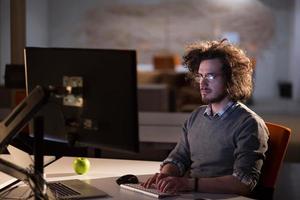 uomo Lavorando su computer nel buio ufficio foto