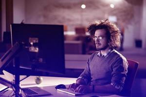 uomo Lavorando su computer nel buio ufficio foto