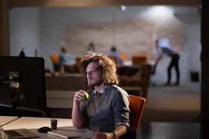 uomo Lavorando su computer nel buio ufficio foto